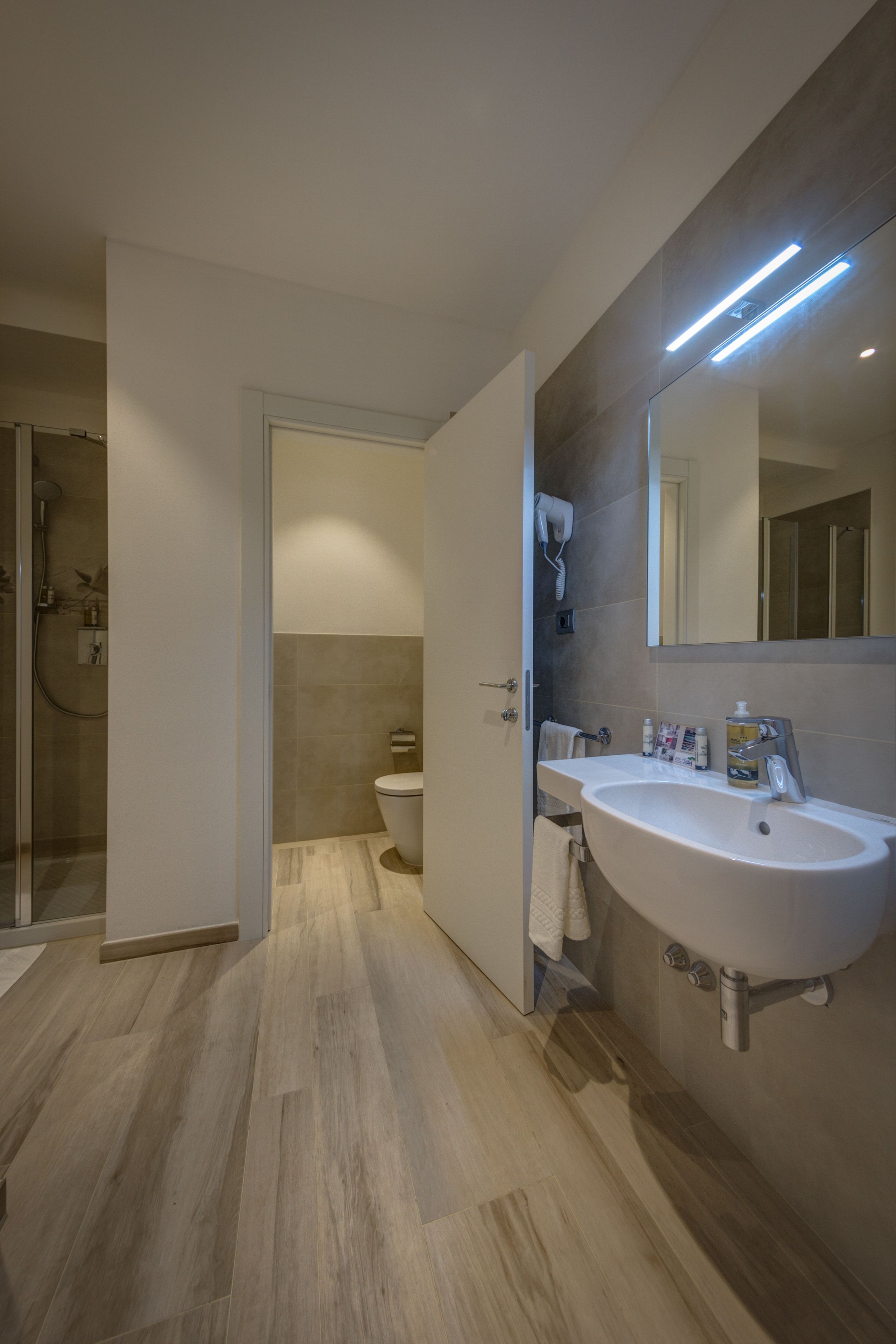 A modern bathroom with a large sink, a mirror, and a shower area.