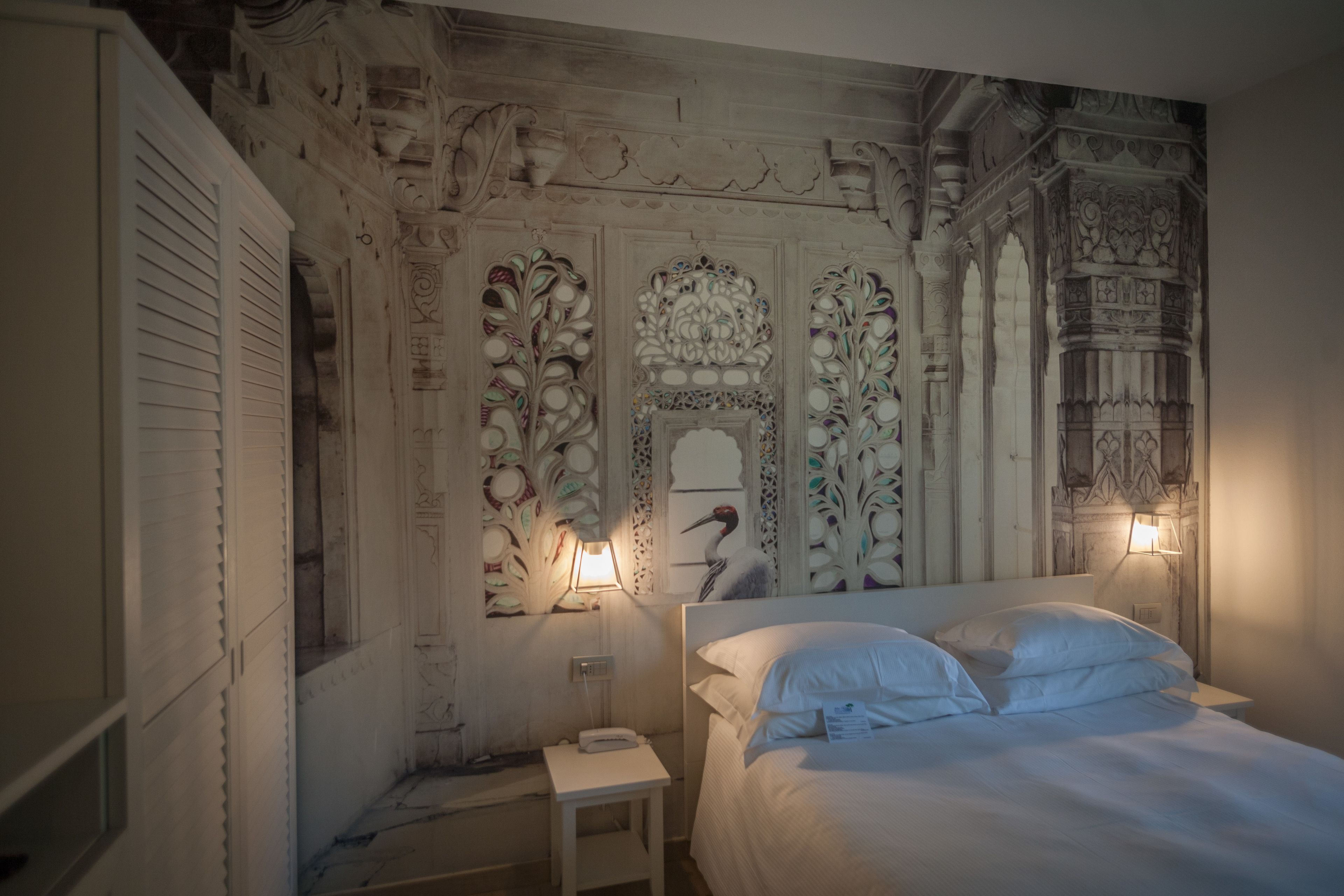 Un dormitorio con una cama grande, dos lámparas de noche y decoraciones ornamentales en la pared.