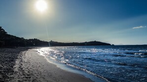 Una playa con cielo despejado y el sol reflejado en el agua.