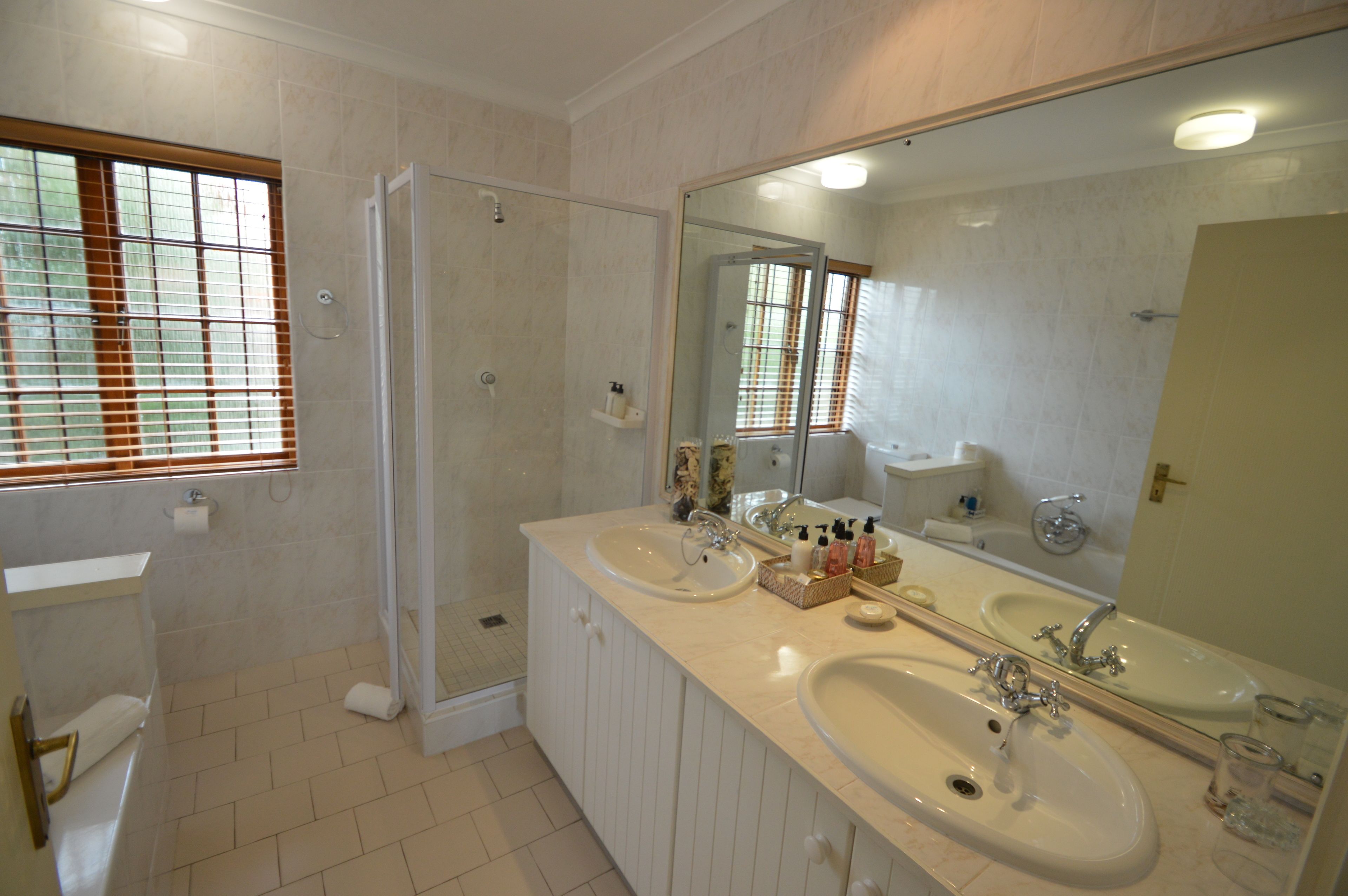 A bathroom with two sinks, a shower, and a large mirror.