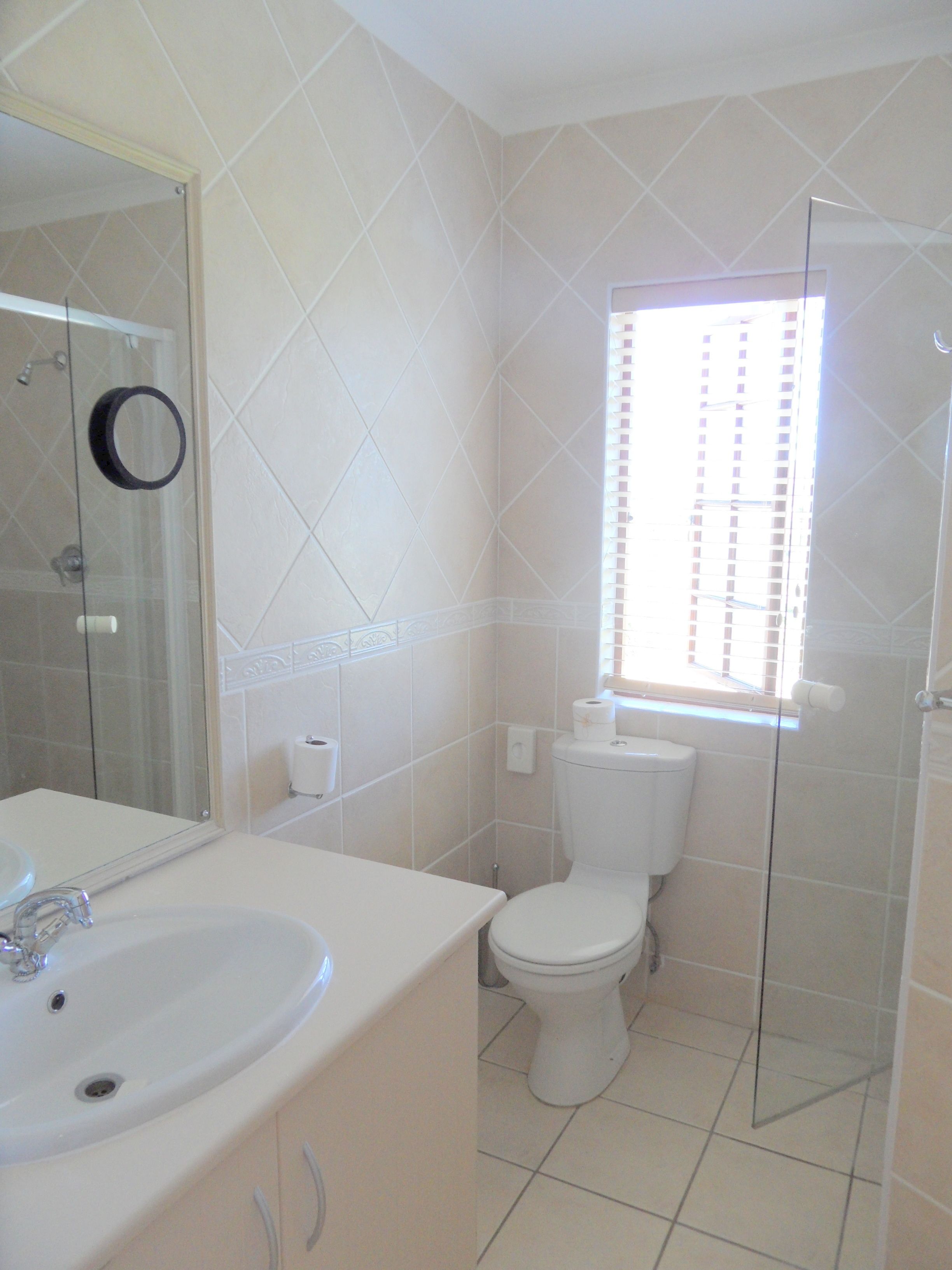 A bathroom with a sink, toilet, and glass shower enclosure.