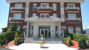 A multi-story hotel with a central entrance, balconies, and a fountain in the front. - Hotel Camino Real (Valdefresno)