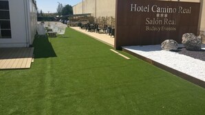 A hotel entrance with a sign reading "Hotel Camino Real Salón Real Bodas y Eventos" and outdoor seating area. - Hotel Camino Real (Valdefresno)
