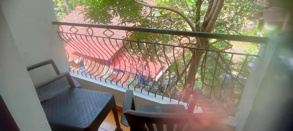 Un balcón con baranda de metal, una mesa y una silla.