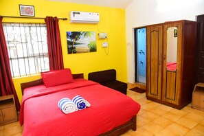 A room with a bed, a wardrobe, a window with curtains, and a wall-mounted air conditioner. - JES Guest House (Majorda)