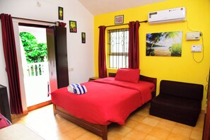 A hotel room with a bed, a chair, an air conditioning unit, and a window with curtains. - JES Guest House (Majorda)