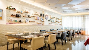 A restaurant with multiple tables and chairs, a brick wall, and shelves with various items on the wall. - Shi Chi Hotel (Kaohsiung)