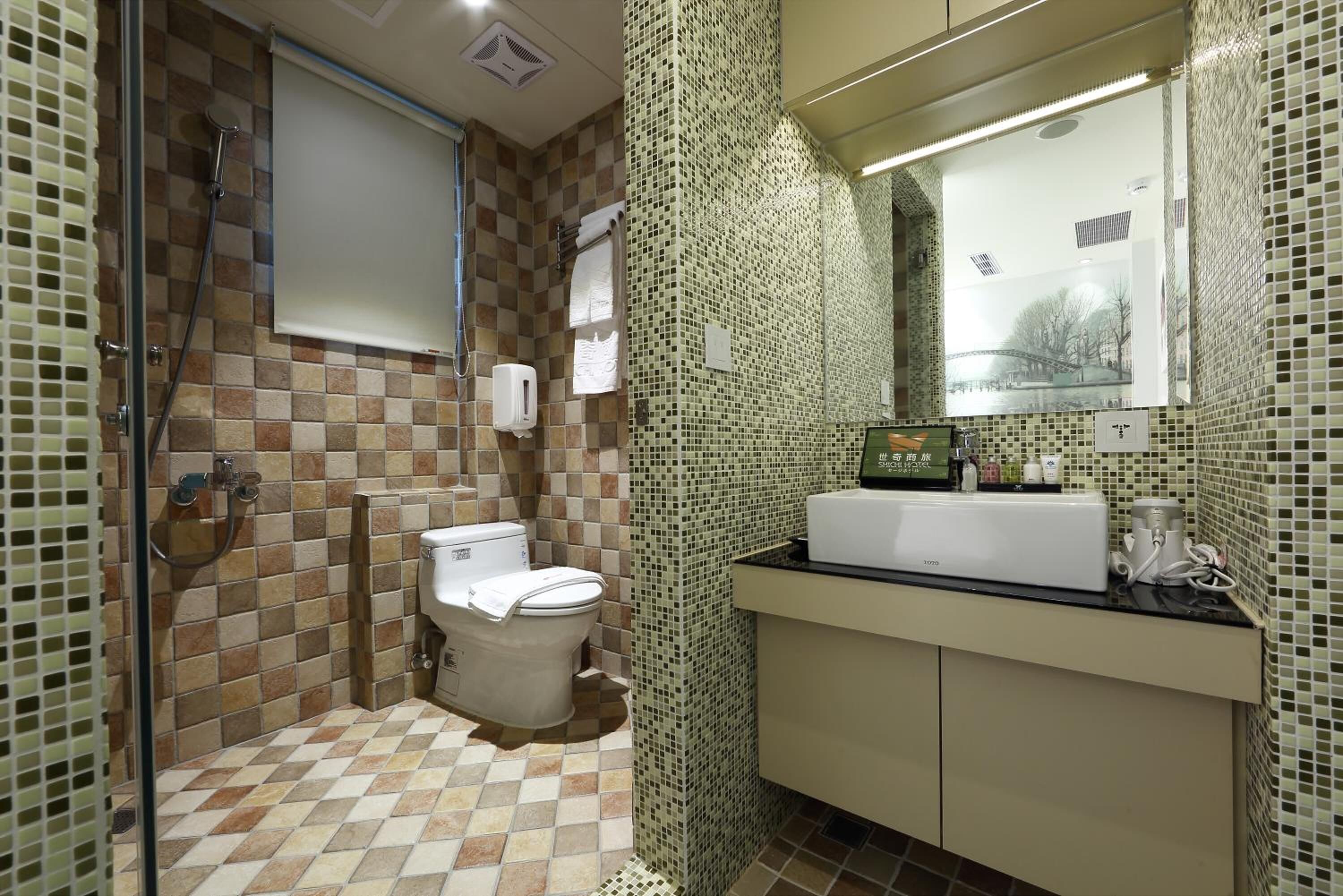 A bathroom with a tiled floor, a toilet, a sink, and a shower.