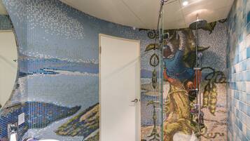 A bathroom with mosaic tile walls, a shower, and a sink.