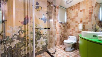 Casa de banho com azulejos de mosaico, cabine de duche, sanita e lavatório verde.