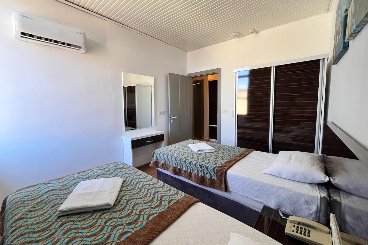 Une chambre d’hôtel avec deux lits, un grand miroir, une armoire et un téléphone.