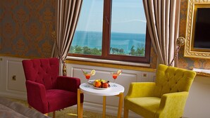 A room with a large window, two armchairs, a small table with fruit and drinks, and a gold-framed mirror. - Hotel Emirhan Palace (Istanbul)