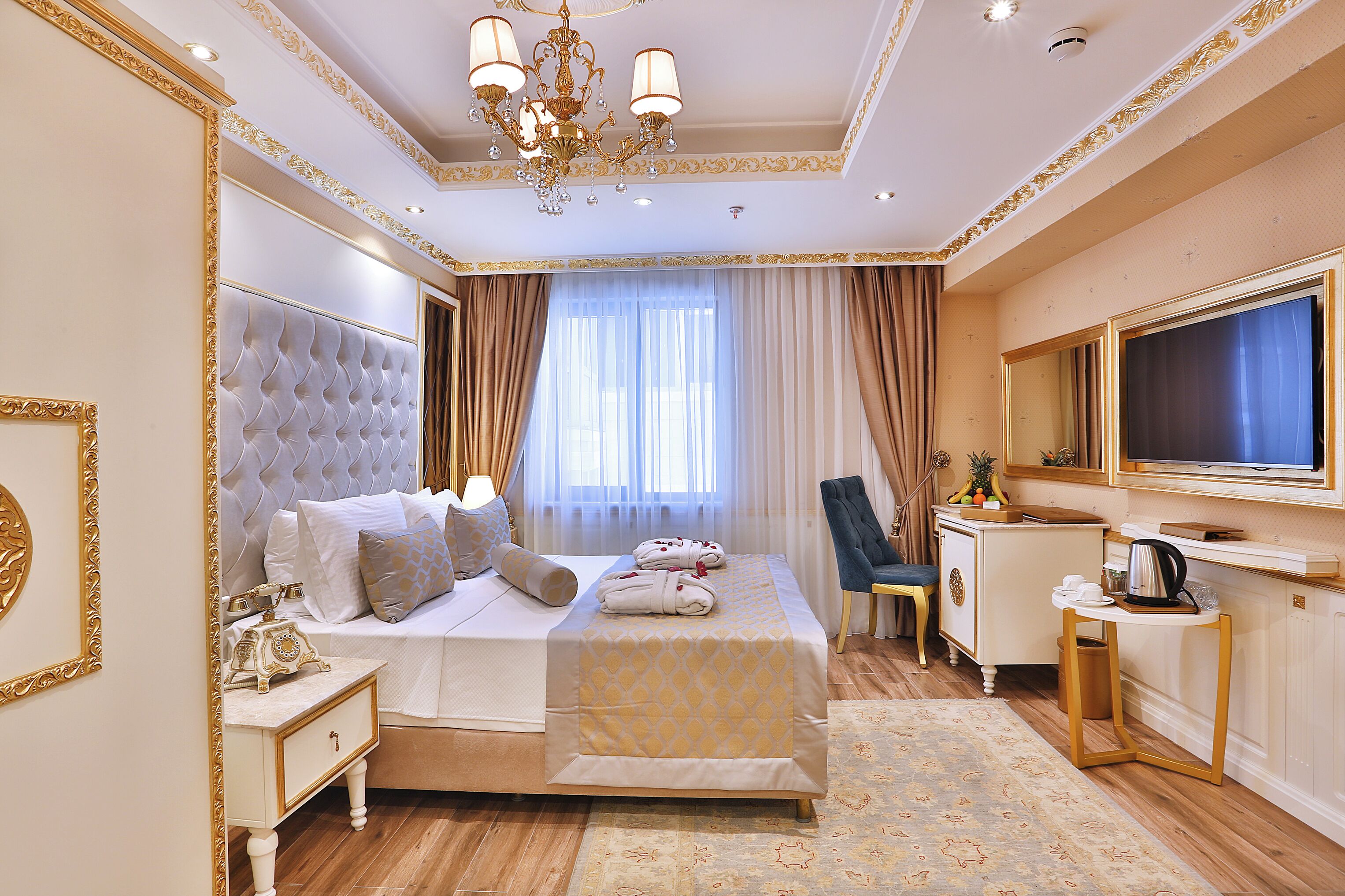 A luxurious hotel room with a large bed, a desk with a mirror, and a television.