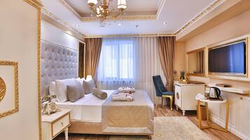 A luxurious hotel room with a large bed, a desk with a mirror, and a television.