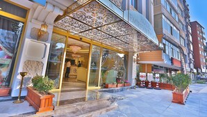 A hotel entrance with ornate architectural details, a reception desk, and potted plants. - Hotel Emirhan Palace (Istanbul)