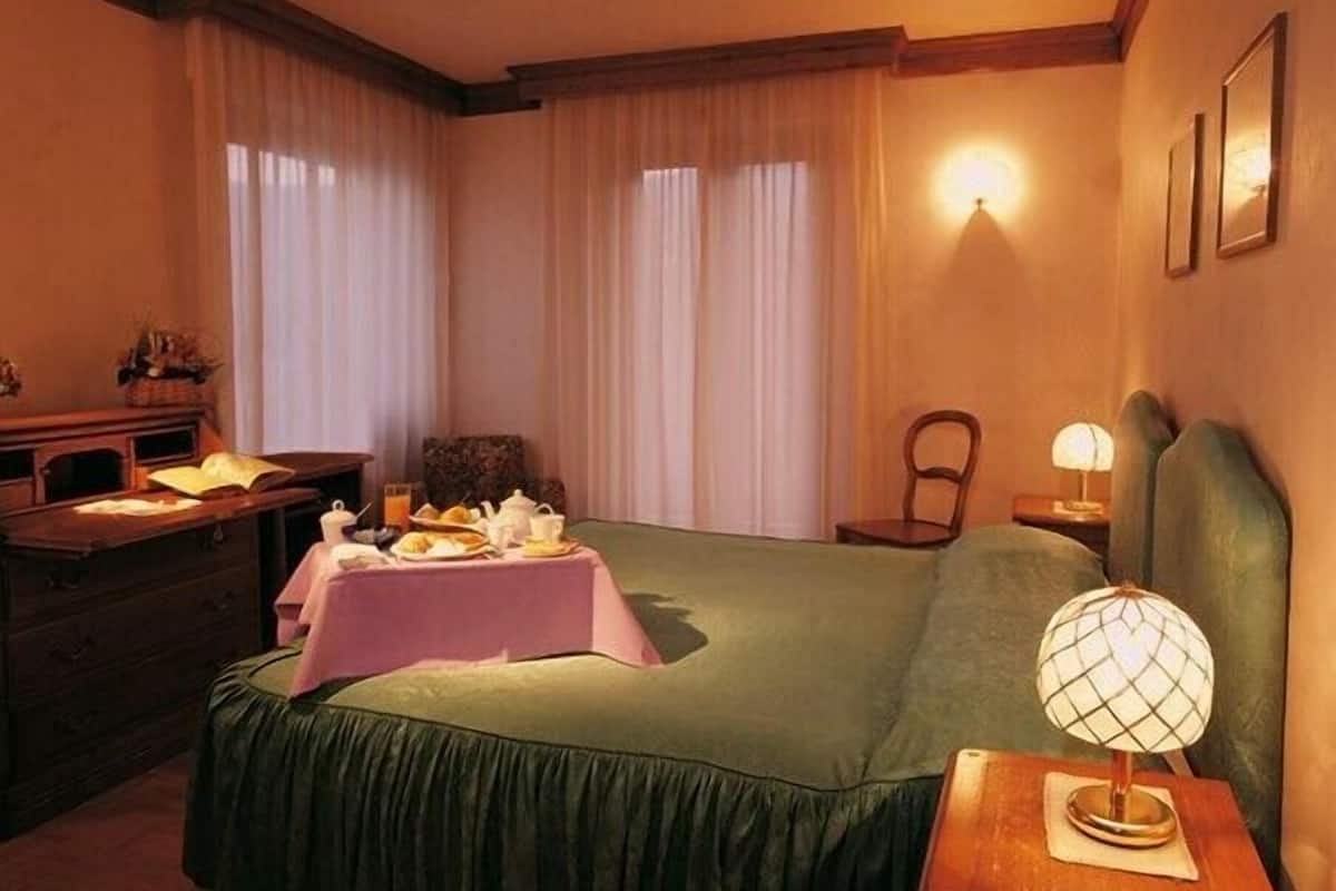 Una habitación de hotel con una cama, un escritorio con lámpara y una silla.