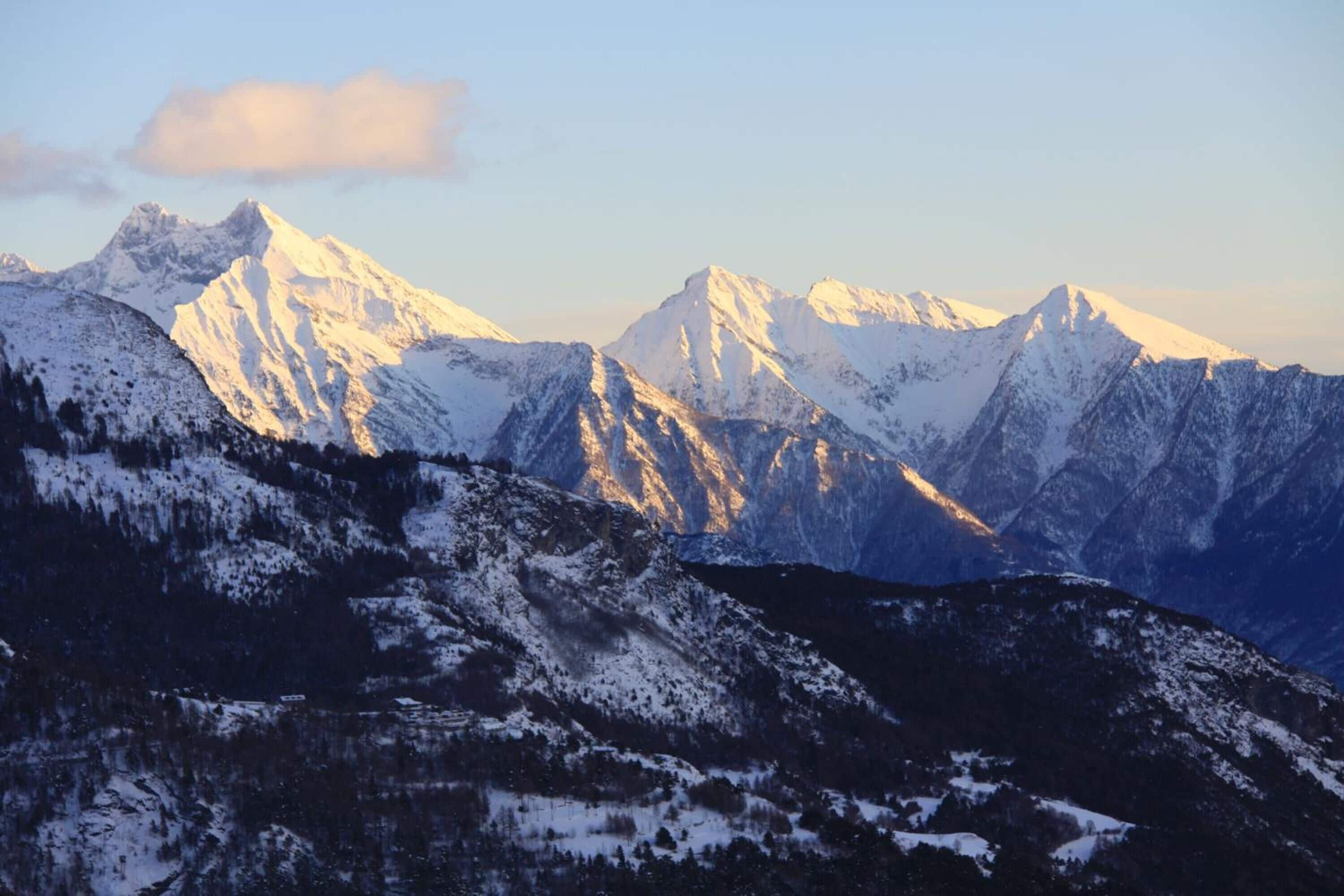A mountainous landscape with snow-covered peaks and a clear sky.