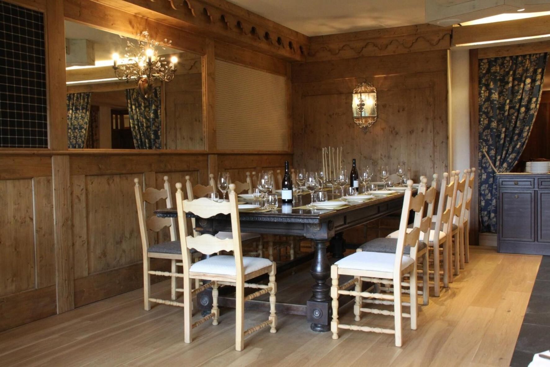 A dining room with a long wooden table set for a meal, surrounded by wooden chairs.