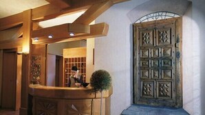 Un área de recepción con un mostrador de madera, una planta en maceta y una puerta grande con un diseño elaborado.