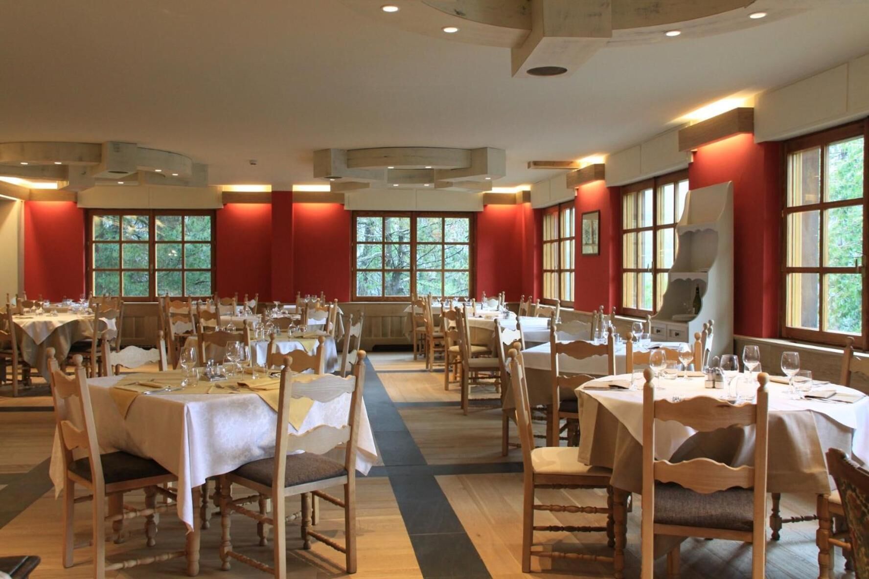Un espace repas avec plusieurs tables dressées pour accueillir les convives, comprenant des chaises en bois et des nappes blanches.