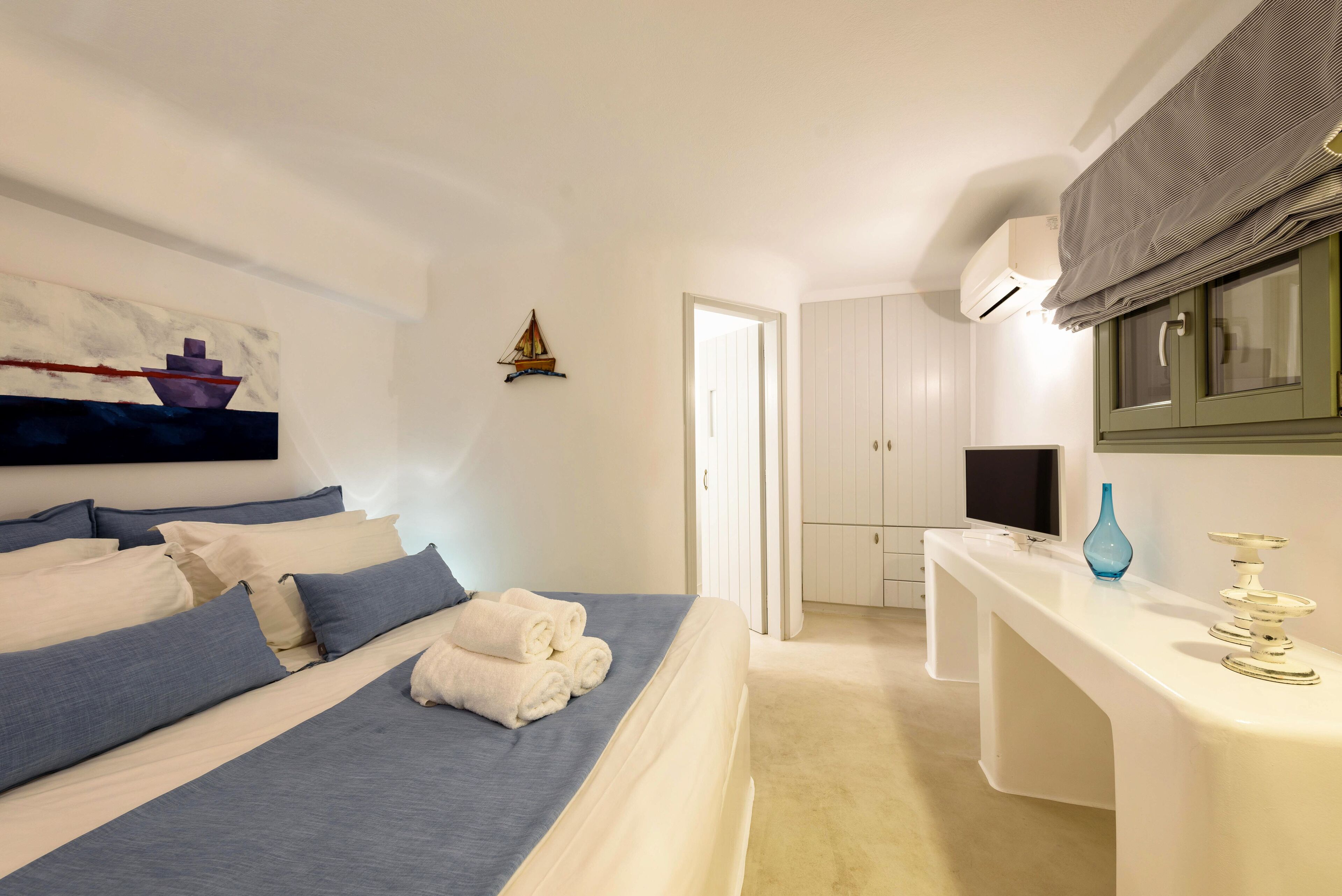 Un dormitorio con cama, escritorio y televisor.
