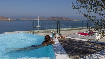 A pool with a clear view of the sea and hills in the background.