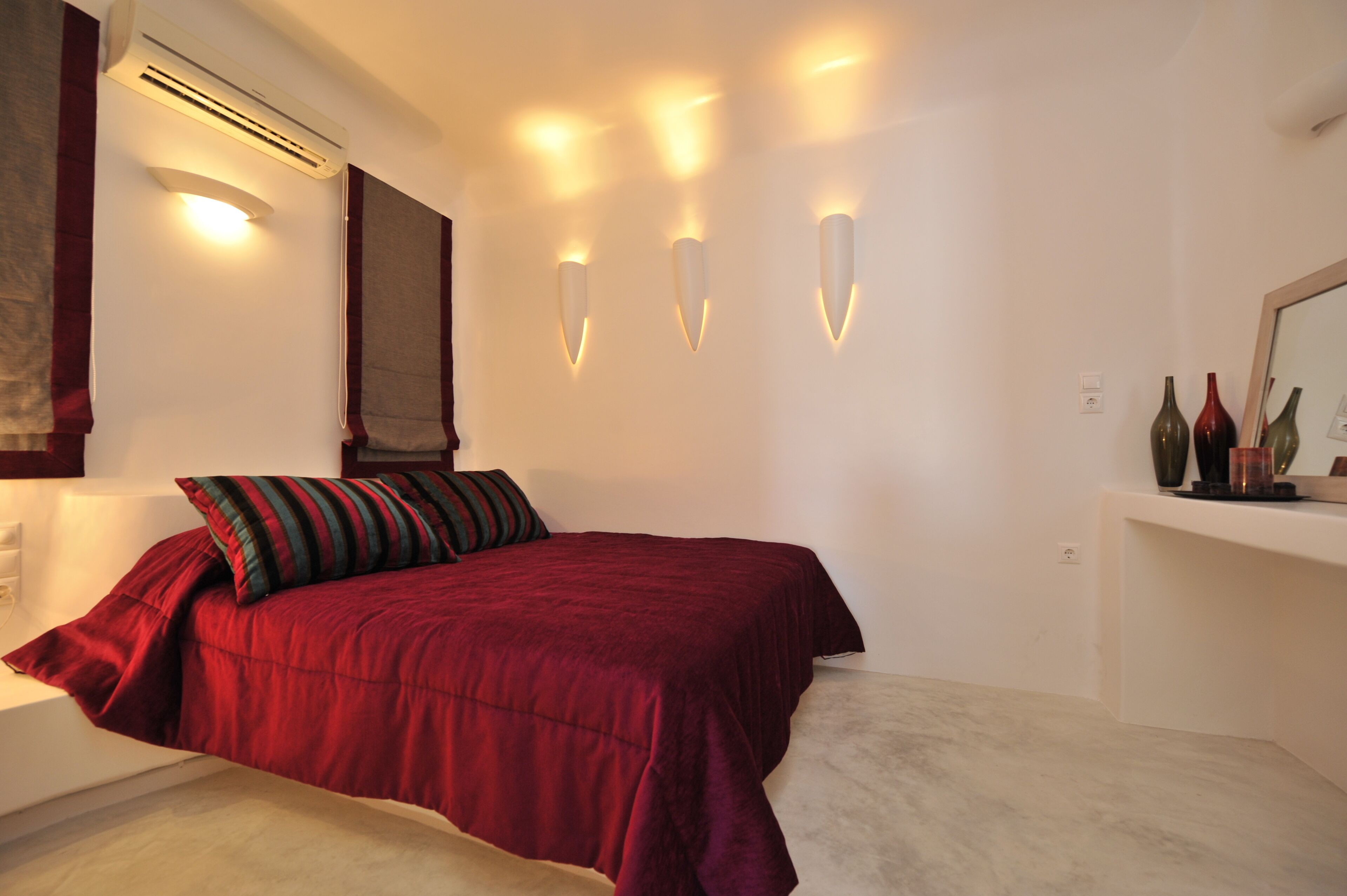 Une chambre à coucher avec un grand lit, une table de chevet, un miroir et des appliques murales.