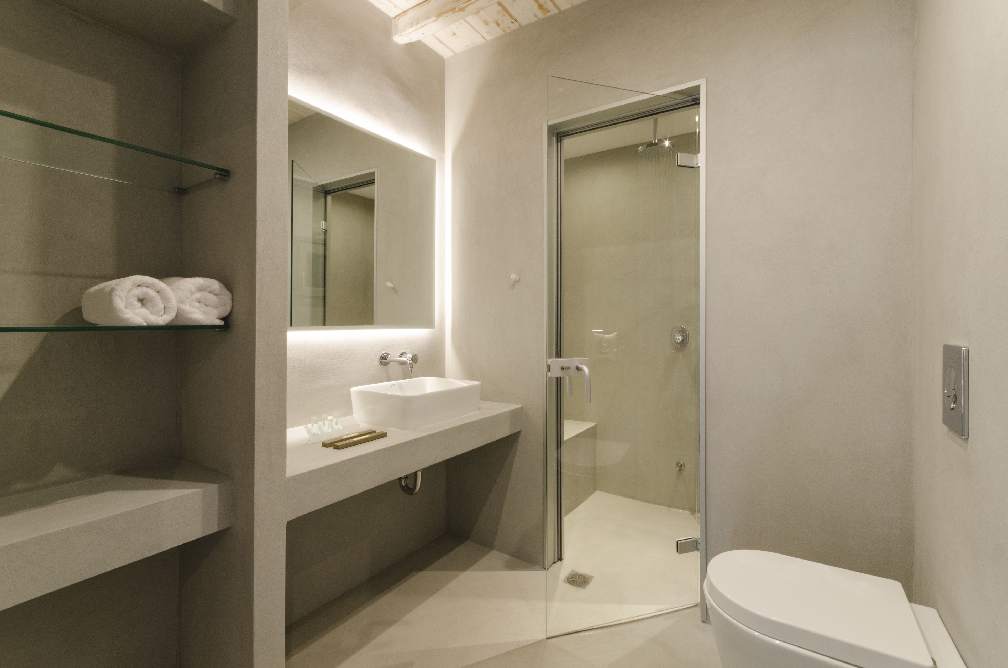 Un baño moderno con ducha de vidrio, lavamanos blanco y un inodoro.