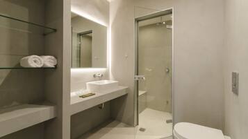 Un baño moderno con ducha de vidrio, lavamanos blanco y un inodoro.