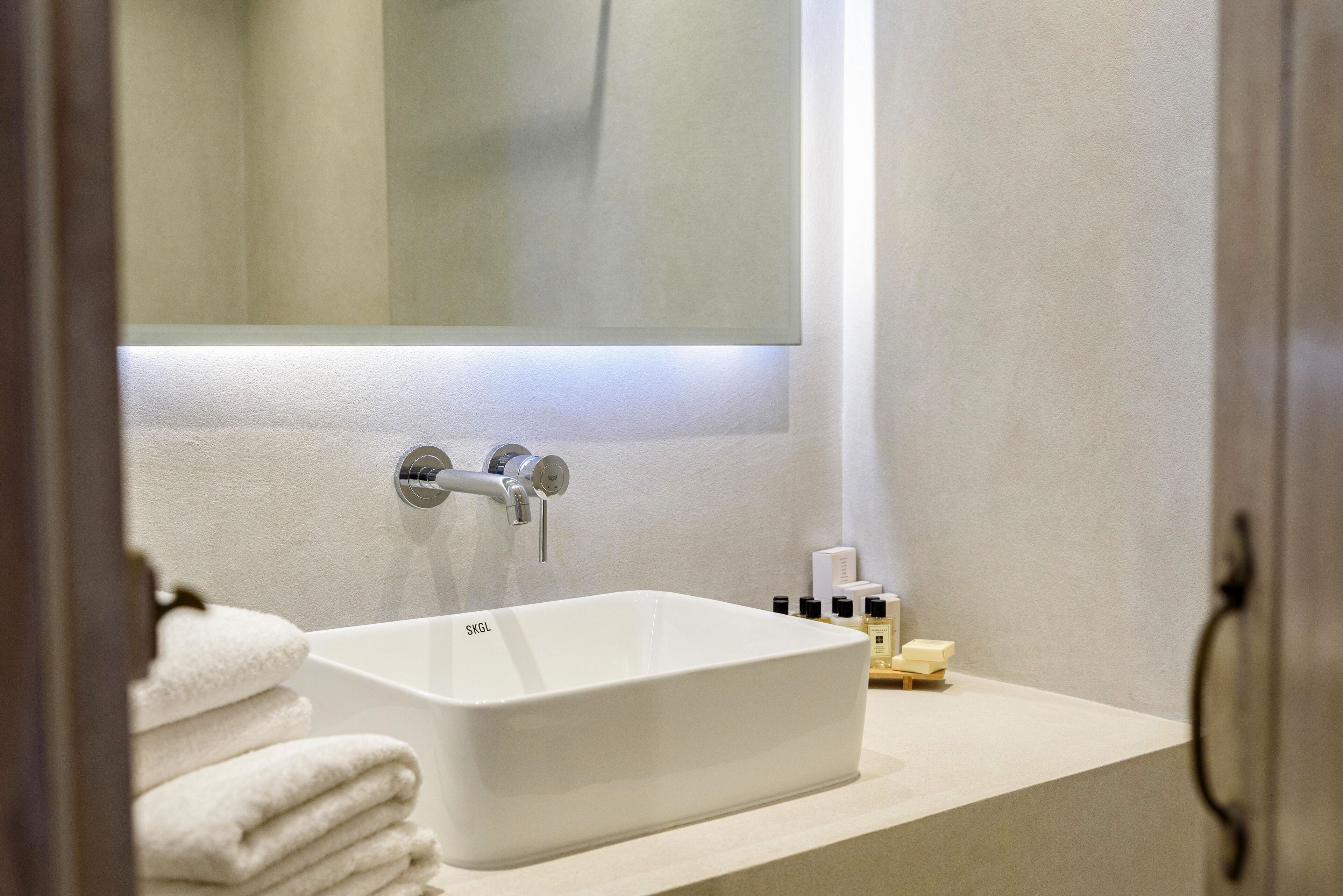 Un baño con un lavabo blanco, un espejo y un perchero para toallas.