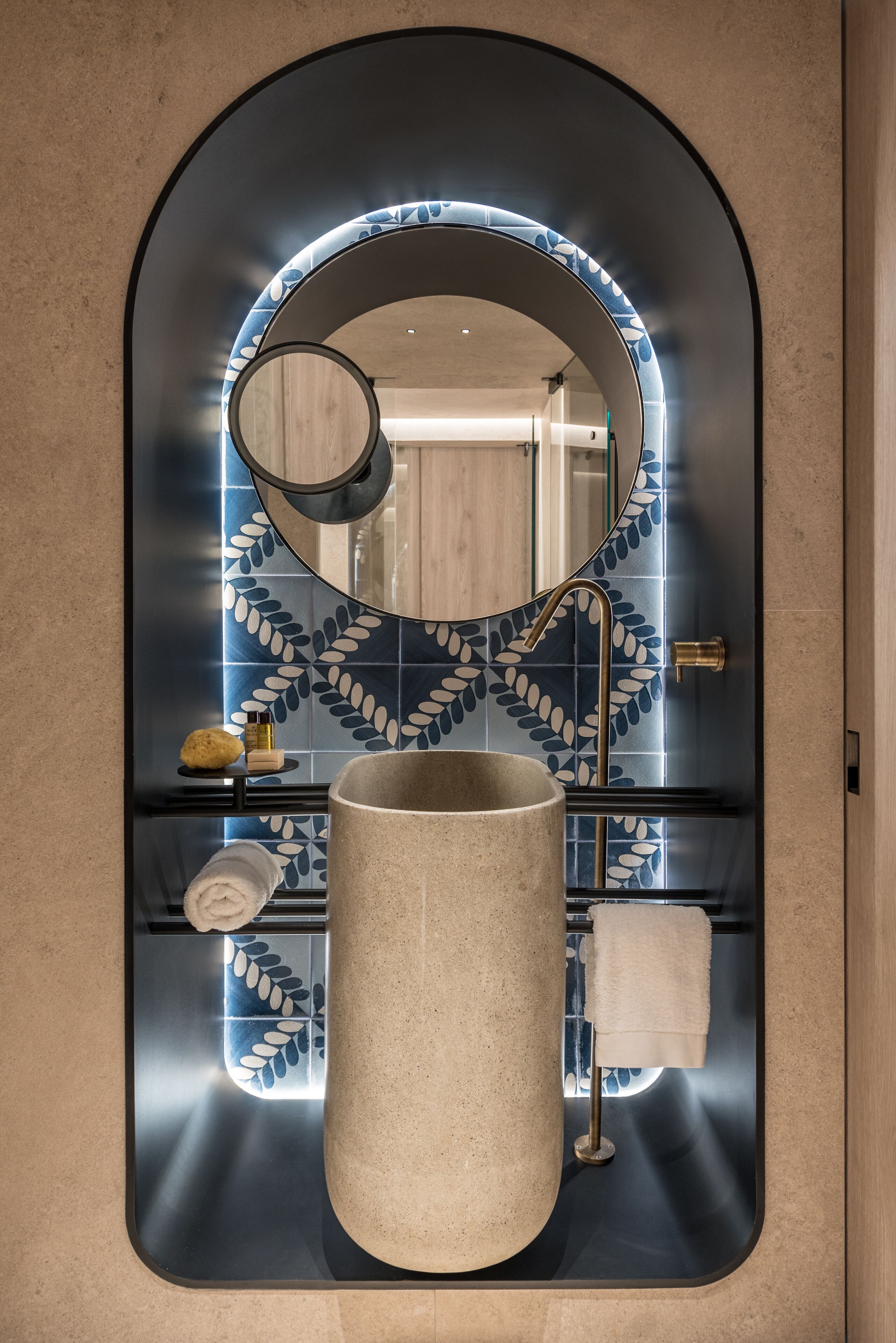 A bathroom with a large mirror, a round sink, and a towel rack.