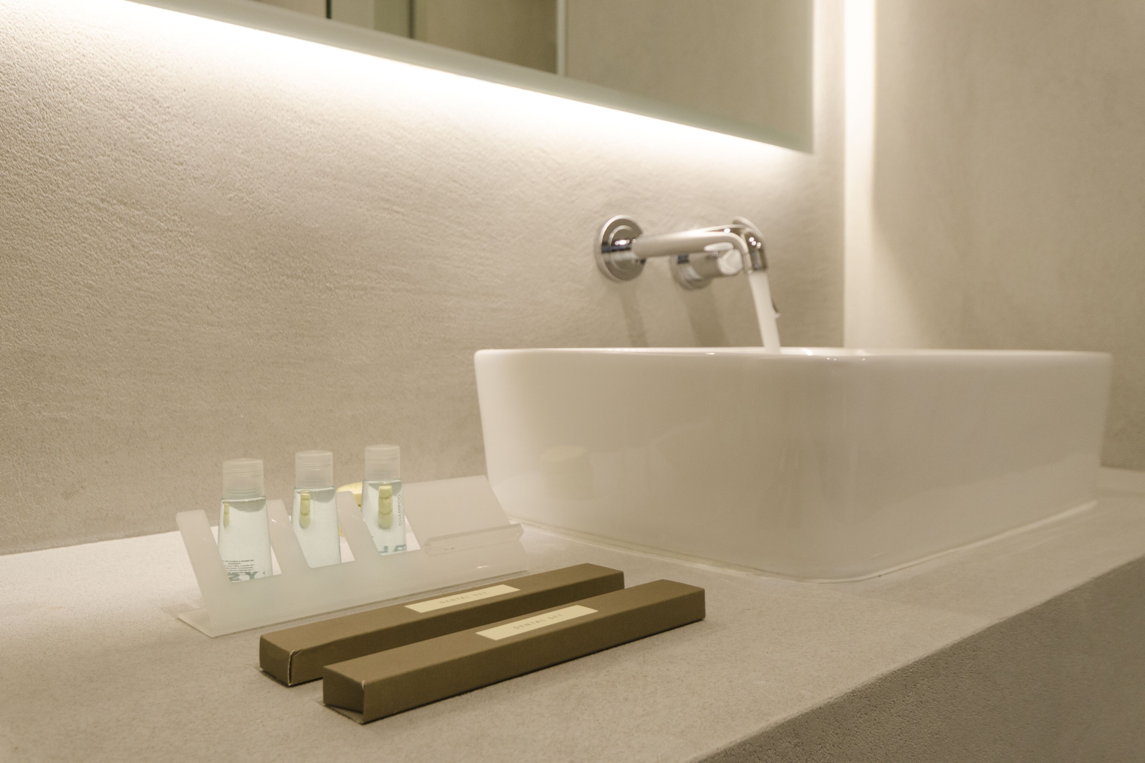 A modern bathroom with a large white sink, a mirror, and a towel rack.