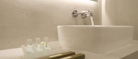 A modern bathroom with a large white sink, a mirror, and a towel rack.
