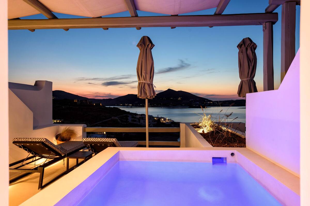 Terraza en la azotea con jacuzzi, sillones de descanso y sombrillas, con vistas a la costa.