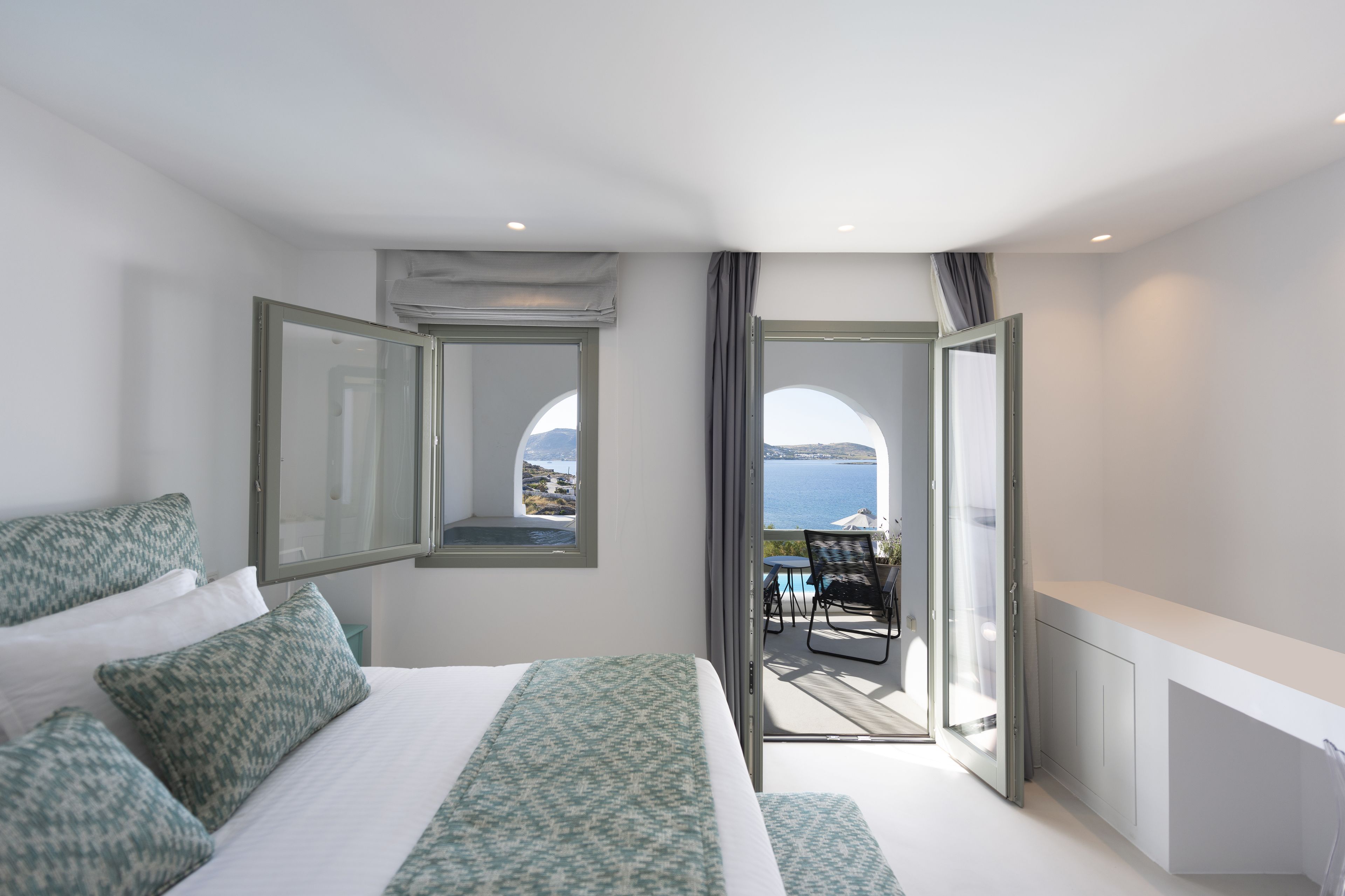 Une chambre à coucher avec un lit, une grande fenêtre et une vue sur la mer.