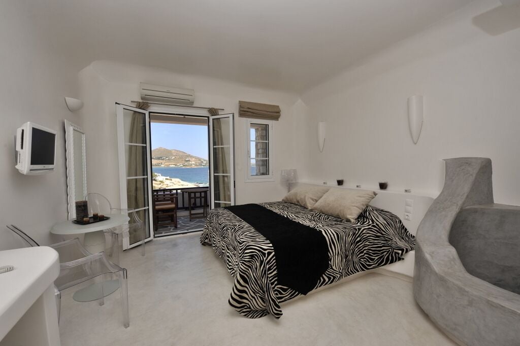 Une chambre avec un lit, un bureau, une chaise et une vue sur la mer.