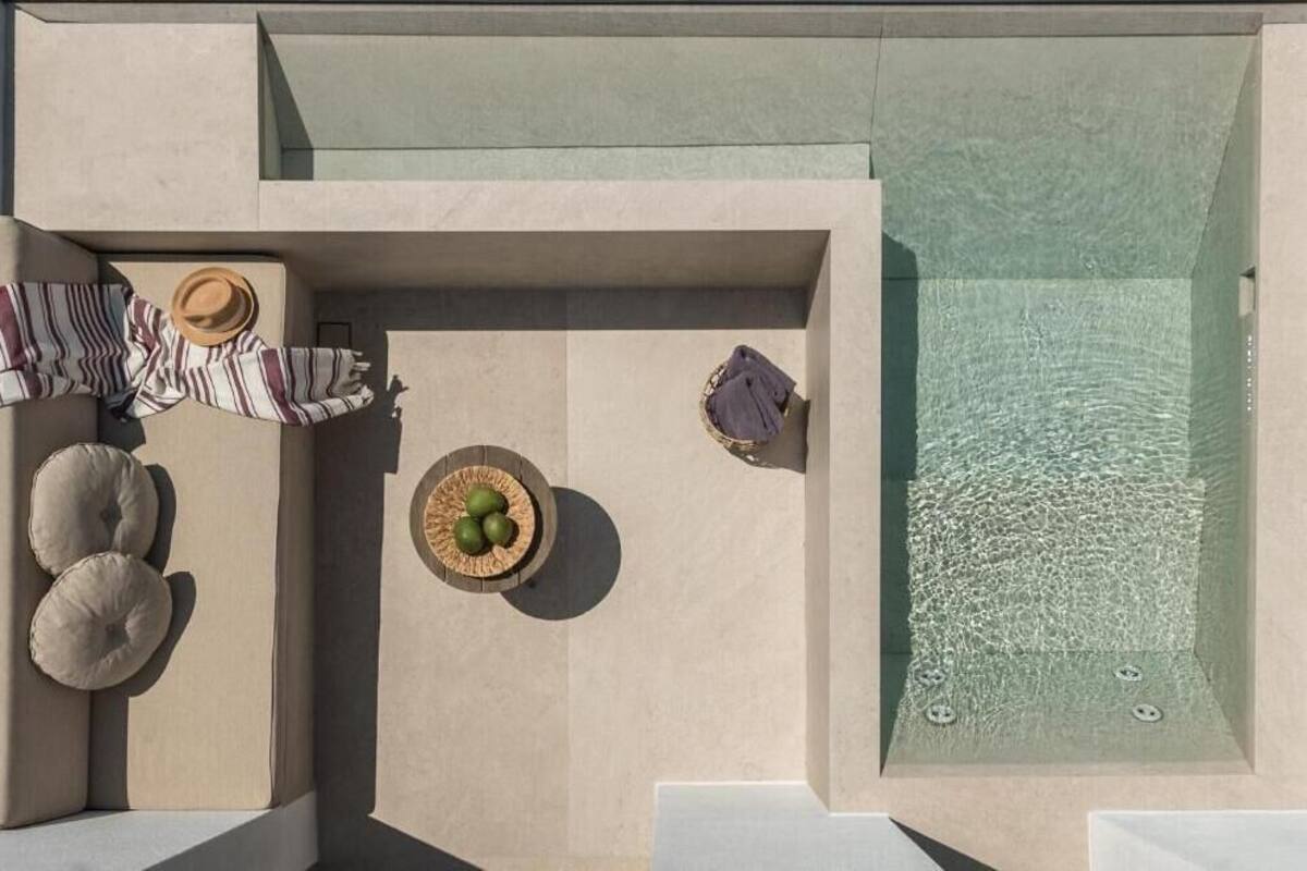 Vista aérea de un moderno espacio exterior con piscina, jacuzzi, sillones de descanso y una pequeña mesa con una cesta.