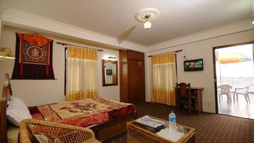 Relax in a traditional room with a comfortable bed, wicker armchair, and large window overlooking a scenic view.