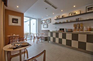 A modern hotel dining area with a checkered bar, seating arrangements, and framed pictures on the walls. - Jules Suites (St. Julian's)