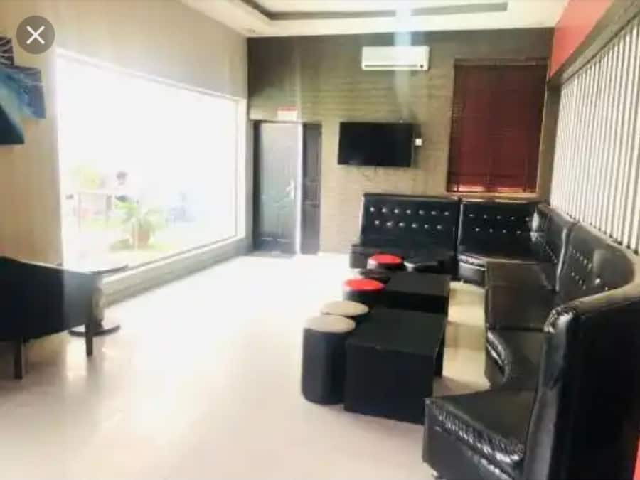 Uma sala de estar moderna com um sofá de couro preto, uma mesa de centro e uma TV de tela plana na parede.