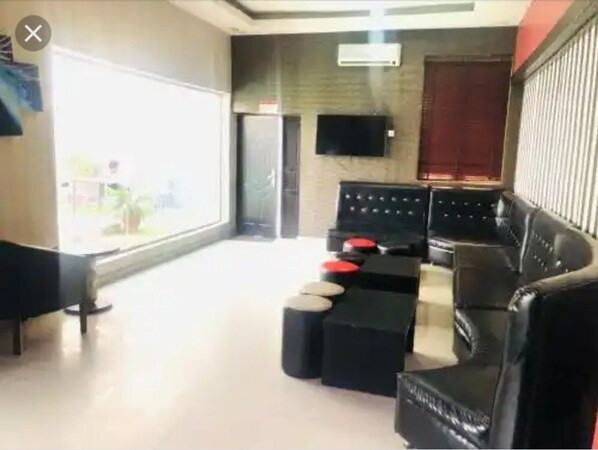 A modern living room with a black leather sofa, a coffee table, and a flat-screen TV mounted on the wall. - Mayors & Diplomat Suites Opebi (Lagos)
