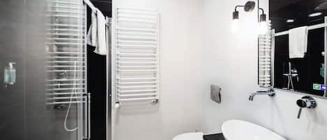 Un baño moderno con cabina de ducha de vidrio, inodoro blanco y encimera negra con lavamanos blanco.