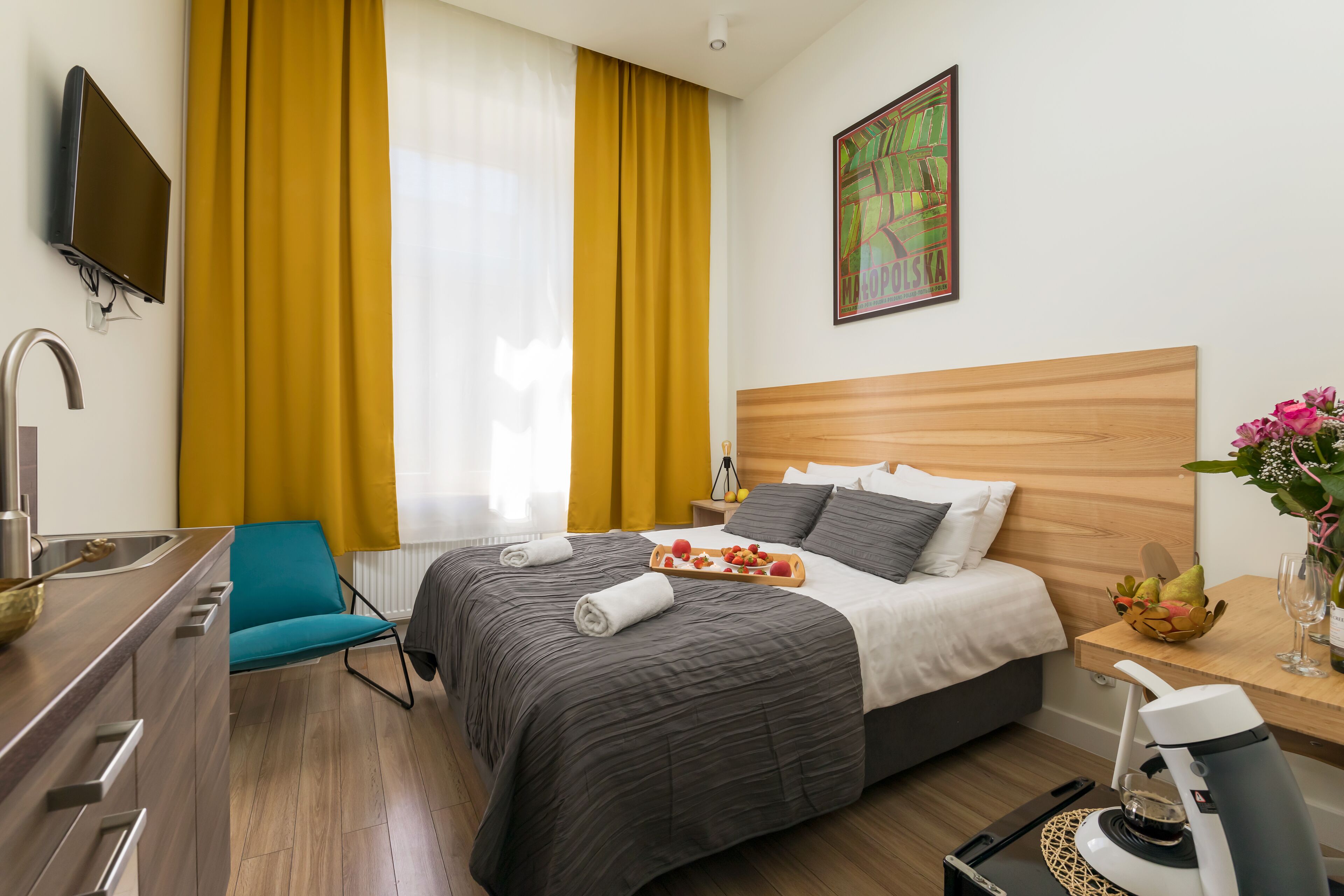 Une chambre d’hôtel équipée d’un lit, d’un bureau, d’une chaise, d’une télévision et d’une fenêtre avec des rideaux.