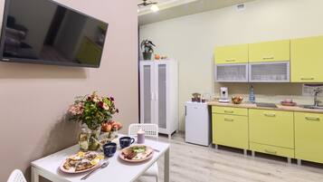 Una cocina moderna con armarios amarillos, un refrigerador blanco y una zona de comedor con una mesa lista para dos.