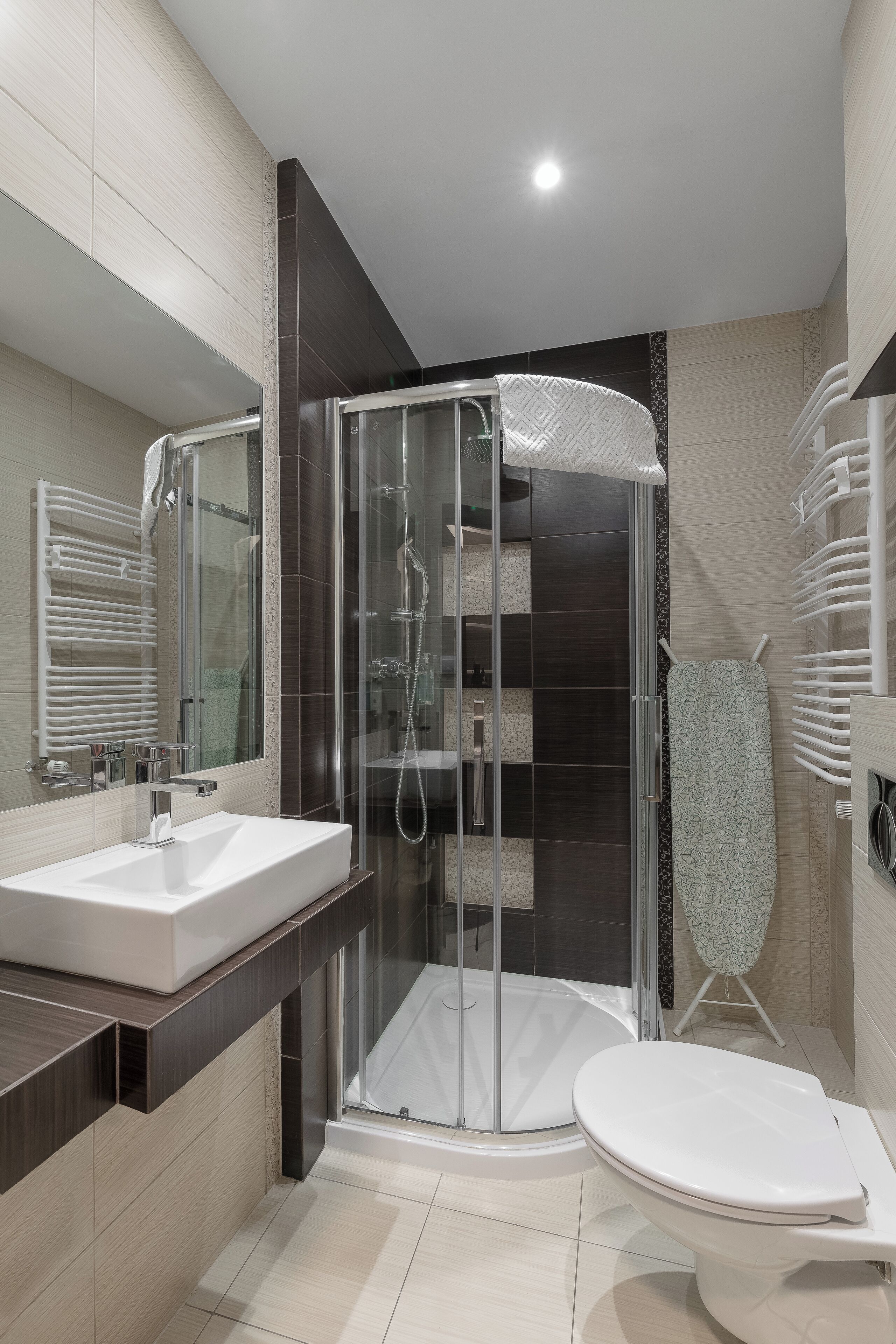 A modern bathroom with a glass-enclosed shower, a white sink, and a toilet.
