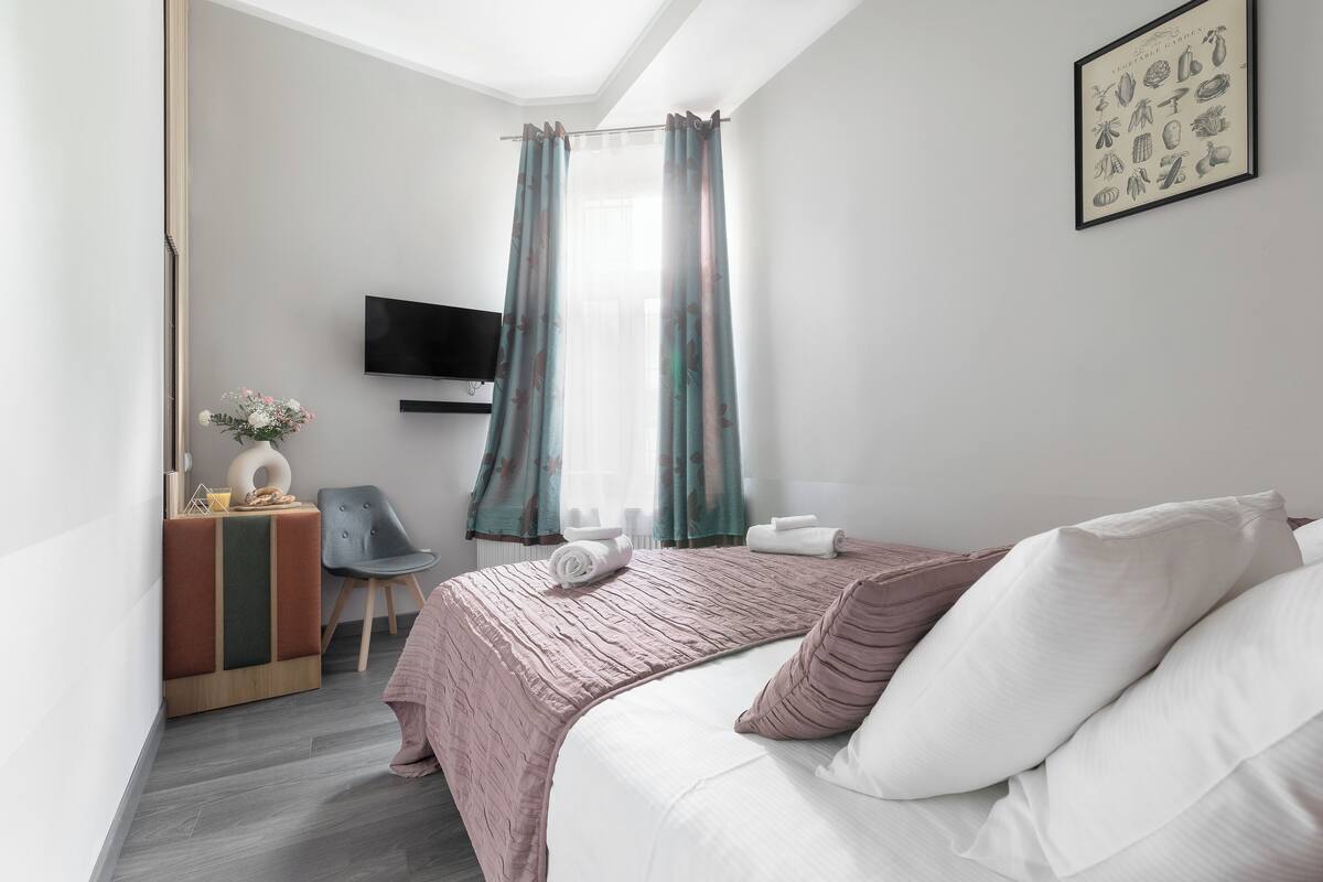 Moderni hotellihuone, jossa on sänky, televisio, työpöytä ja tuoli.