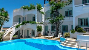 A white building with a pool, stairs, and outdoor seating. - Kurmulis Studios (Chania)