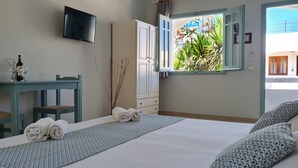 A bedroom with a bed, a desk, a TV, and a window with a view of the outside. - Kurmulis Studios (Chania)