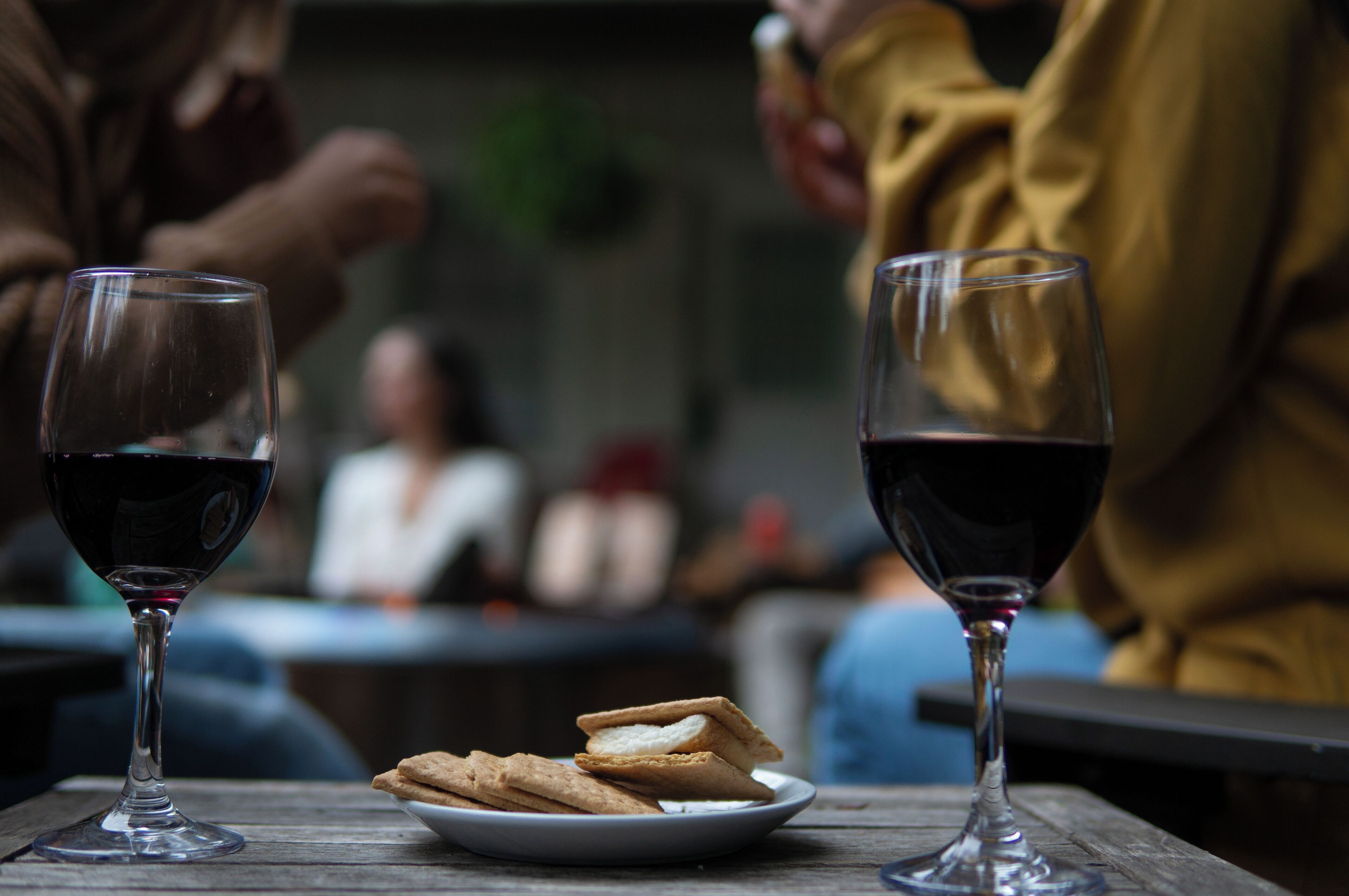 Two wine glasses on a table with a plate of cookies.
