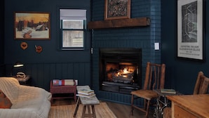 A cozy room with a fireplace, a bed, a small table, and a chair. - Outpost Inn (Highlands)